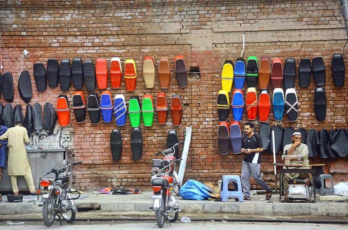 Vendor selling and displaying colorful fancy motorcycle seats to attract the customers during his roadside setup at Sarki Area