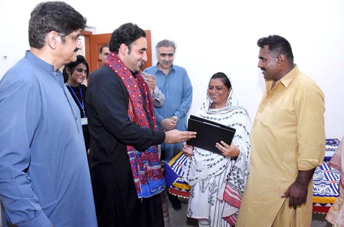 Chairman PPP and Foreign Minister Bilawal Bhutto Zardari giving away house ownership right document to flood victims under the Sindh People's Housing Scheme during a visit to a house built for them at village of Vikia Sangi