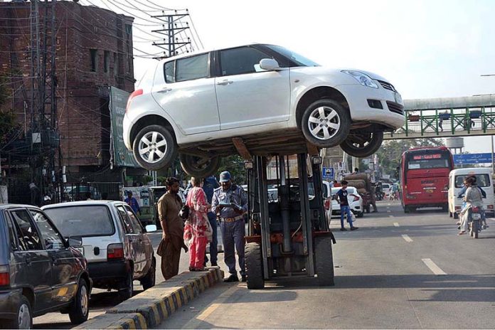 A warden lifting car with the help of lifter to stop illegal parking