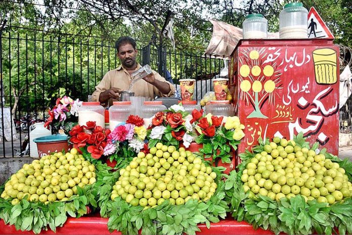 A vendor preparing and selling lemonade at his roadside setup