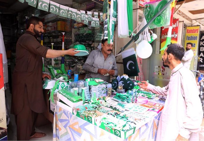 A vendor displaying and selling 14th August related stuff to attract customers at his roadside setup in the city