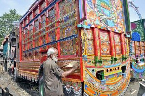 A truck painting artist preparing a body of a delivery truck at his workplace