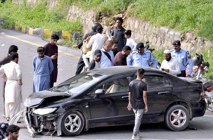 Security personnel and people gathered around a damaged car after an accident on Faisal Avenue near Zeropoint