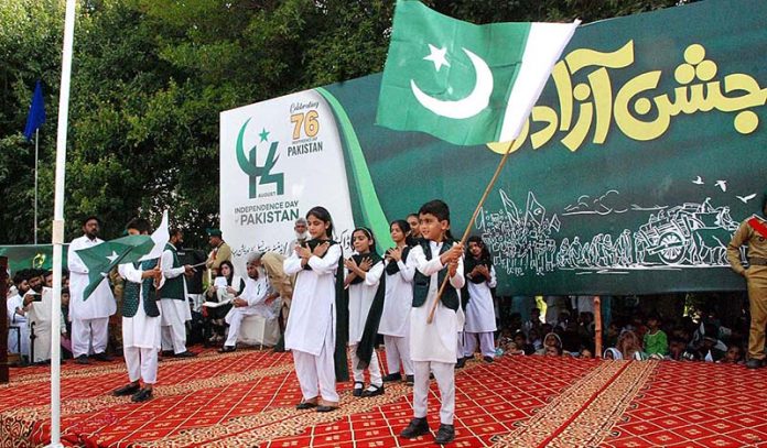 Children are reciting the National anthem and waving the National flag during a ceremony organized on the occasion of 77th Independence Day celebration