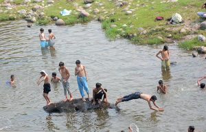 Youngsters jumping and bathing in the Rawal dam adjacent Nallah in the Federal Capital. 