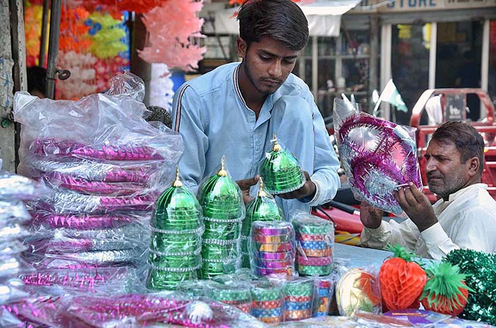 A vendor arranging and displaying Eid Milad-un-Nabi (PBUH) related ...