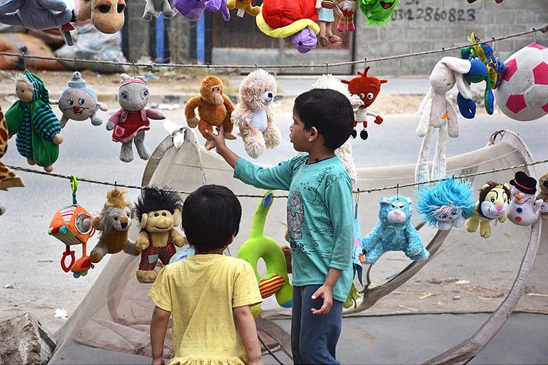 Children selecting old toys displayed by vendor at roadside stall