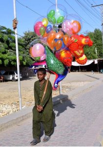 A young vendor selling balloons to attract the customers at Al Murtaza House Road