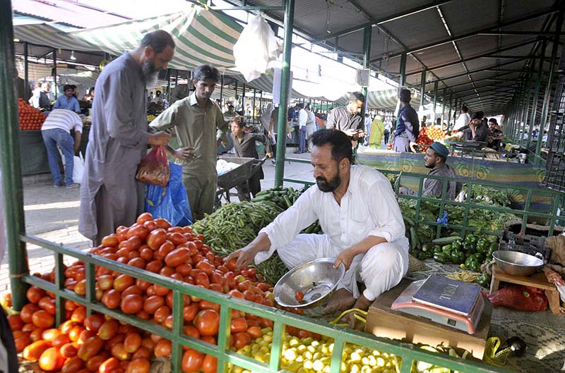 Pakistani shoppers purchase vegetables from a stall inside a
