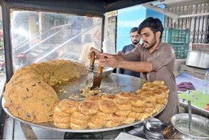 A shopkeeper preparing popular traditional food of Lahoris anda tikki tawa fry to attract the customers at his setup