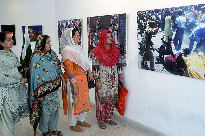 Visitors taking interest in photos during exhibition in connection with ...