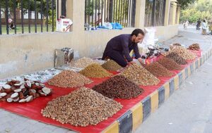 A vendor displaying dry fruit to attract customers at roadside setup. 