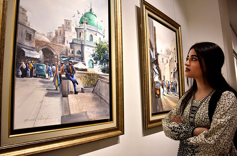 Female Visitor keenly viewing painting during the painting exhibition “Lahore Lahore hai” by Zahid Ashraf at Ejaz Art Gallery