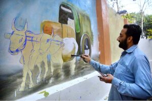 Artist busy in making wall paintings in front of the Press Club wall