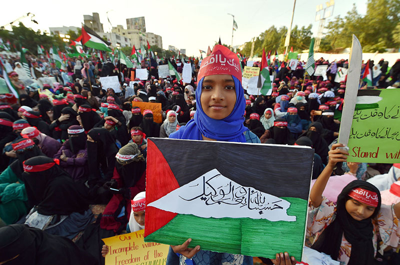 Women holding posters and banners as they attend the solidarity conference for the people of Palestine organized by Pakistan Markazi Muslim League at Shahra e Quaid