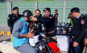 Chief Traffic Police Officer Dr. Zahid Ullah distributing helmets, mugs and history books of Quaid-e-Azam to a motorcyclist on the occasion of Quaid-e-Azam day at Khyber Road. 