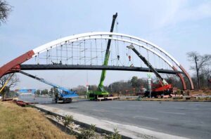 CDA workers busy installing pedestrian bridge with the help of cranes at Srinagar Highway in the Federal Capital