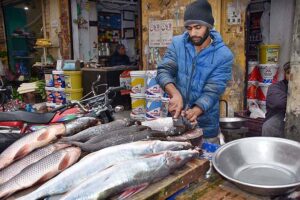 A vendor preparing fish for customers at his roadside setup. 