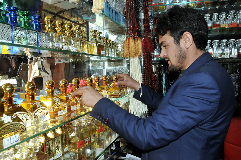 A shopkeeper arranging and displaying perfumes to attract the customers ...