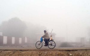 A cyclist on his way during heavy fog in the city during morning time. 