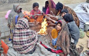 A gypsy family sitting around fire to keep them warm at Latifabad during cold weather in the city.