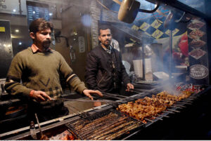 Vendors preparing traditional Chicken Tikka and kabab to attract customers outside their shop at Rustam Park