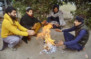 Vendors sitting around fire to keep them warm during cold weather in the city. 