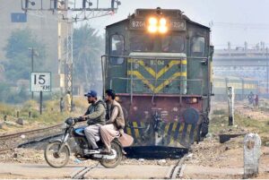 Motorcyclist crossing railway track while train is approaching.