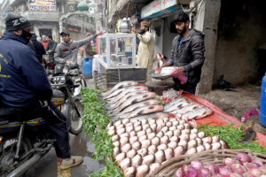 A vendor selling fish to the customers at his roadside setup. 