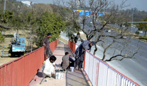  Workers paint the grills of a pedestrian bridge on Srinagar Highway.