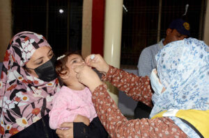 A lady health worker is administering Polio drops to a child during 7 days Anti Polio Campaign in the city. 