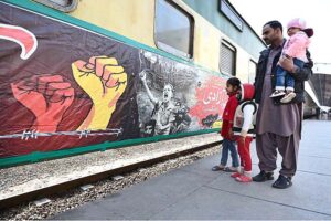 Passengers viewing banner installed on a train to mark Kashmir Solidarity Day at Cantt Railway Station