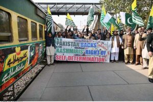 Passengers viewing banner installed on a train to mark Kashmir Solidarity Day at Cantt Railway Station