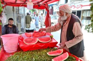 An elder vendor selling watermelon to attract customers at Mission Road.