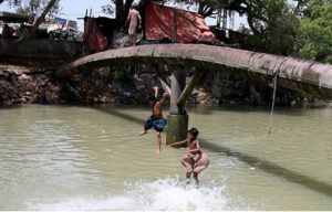 Youngsters jumping and bathing in the canal to get relief from hot weather in the city