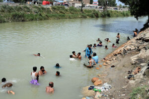 Youngsters jumping and bathing in the canal to get relief from hot weather in the city