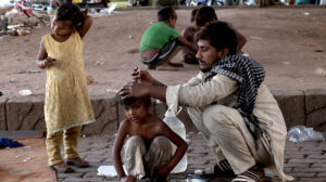 A Gypsy father carefully cuts his son's hair at their roadside temporary home