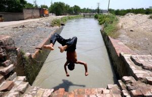 Youngster diving in a canal for bath to get relief from hot weather