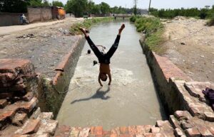 Youngster diving in a canal for bath to get relief from hot weather