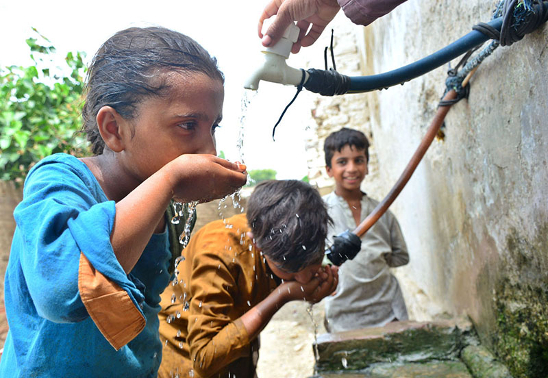 Children quenching their thirst from a water tap in Latifabad.