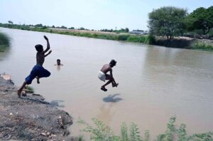 Youngsters jumping and bathing in a Canal to get some relief from scorching hot and humid weather in the city