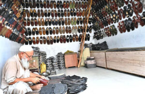 An elderly cobbler skillfully prepares Peshawari chappal for customers at his workplace.