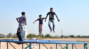 Young boys enjoy jumping on a roadside trampoline setup.