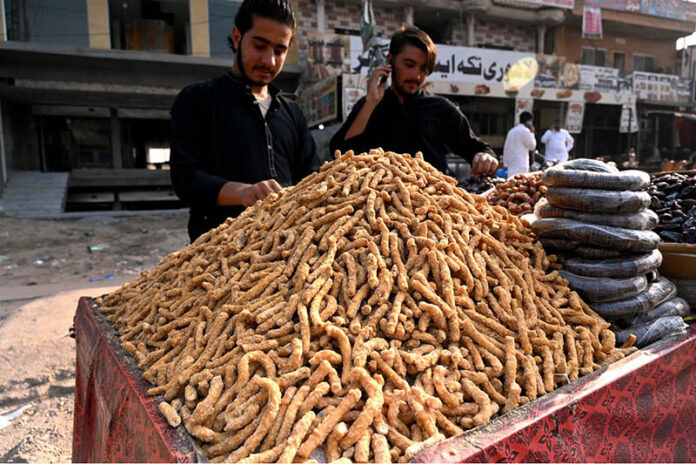 Vendor arranging and displaying traditional sweets item at roadside in ...