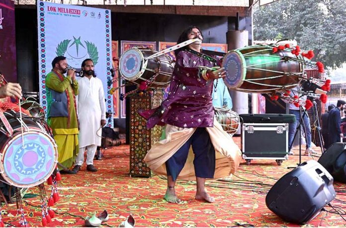 A drumbeater plays while spinning heavy hanging drums around him during the opening ceremony of the 'Annual Ten-Day Folk Festival Lok Mela' at Lok Virsa in the federal capital