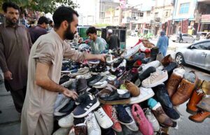 A vendor sells and displays second-hand imported shoes to attract customers on Faqirabad Road.