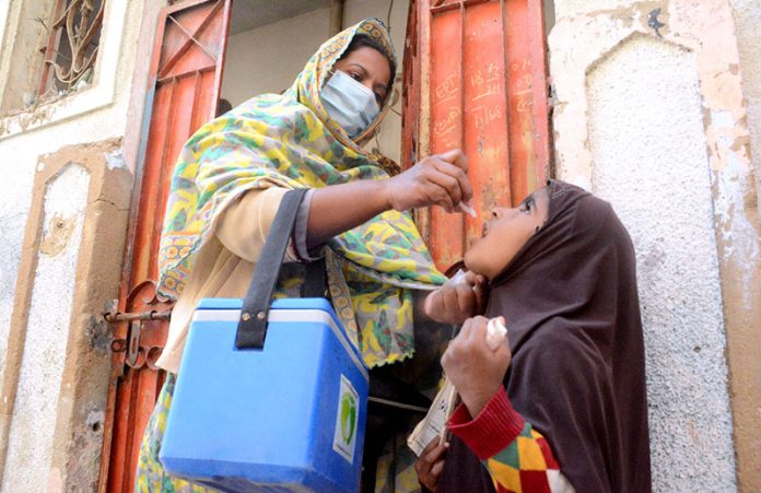 A lady health worker administering polio drops to a child during anti-polio campaign in the city