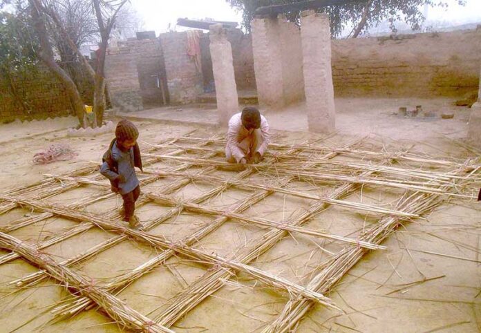 A worker is busy crafting a stick roof for his home, skillfully arranging the materials to ensure a sturdy and functional structure