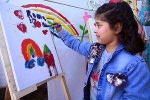 Woman making a painting on a child face during the 2nd Day of PDA Food & Culture family Festival with the support of UNICEF at Regi Model Town Park