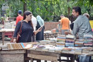 People are engaged in selecting and buying old books from the weekly stalls on the roadside of Mall Road.